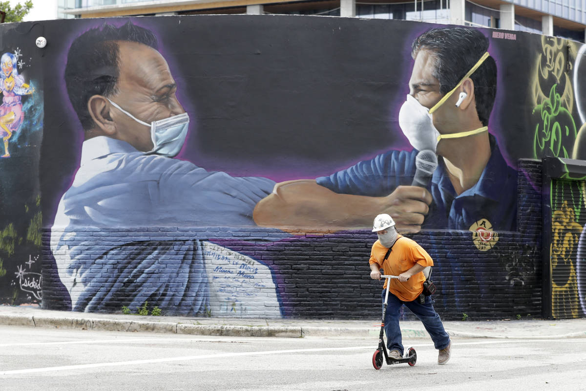 A construction worker rides a scooter past a mural by Hiero Veiga of billionaire businessman Mo ...