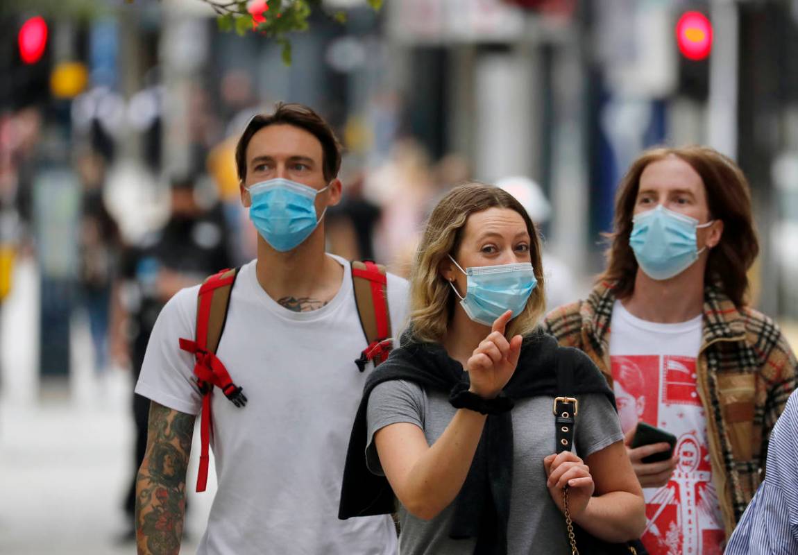 Shoppers wearing protective face masks walk along Oxford Street in London, Tuesday, July 14, 20 ...