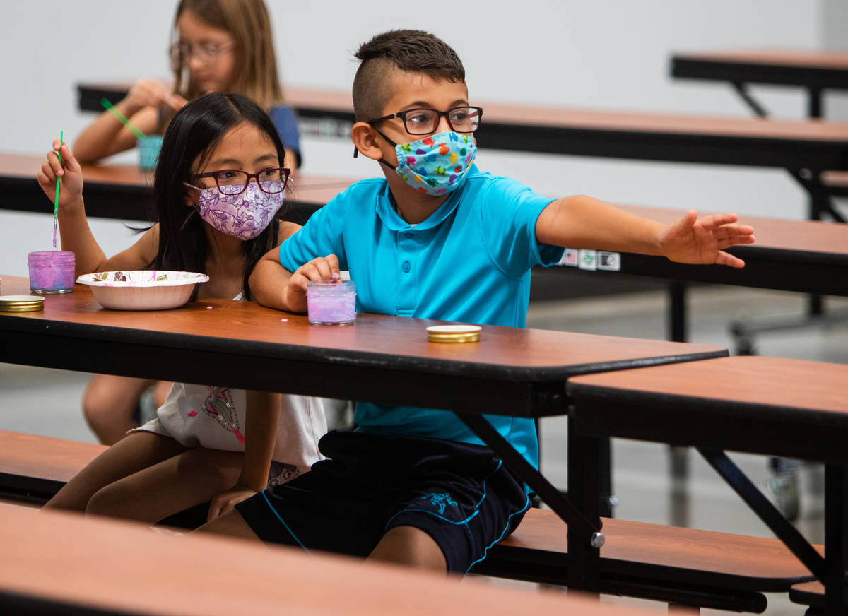 Ellura H., 8, and Giani B., 8, mix paints in the cafeteria as Giani reaches toward another camp ...