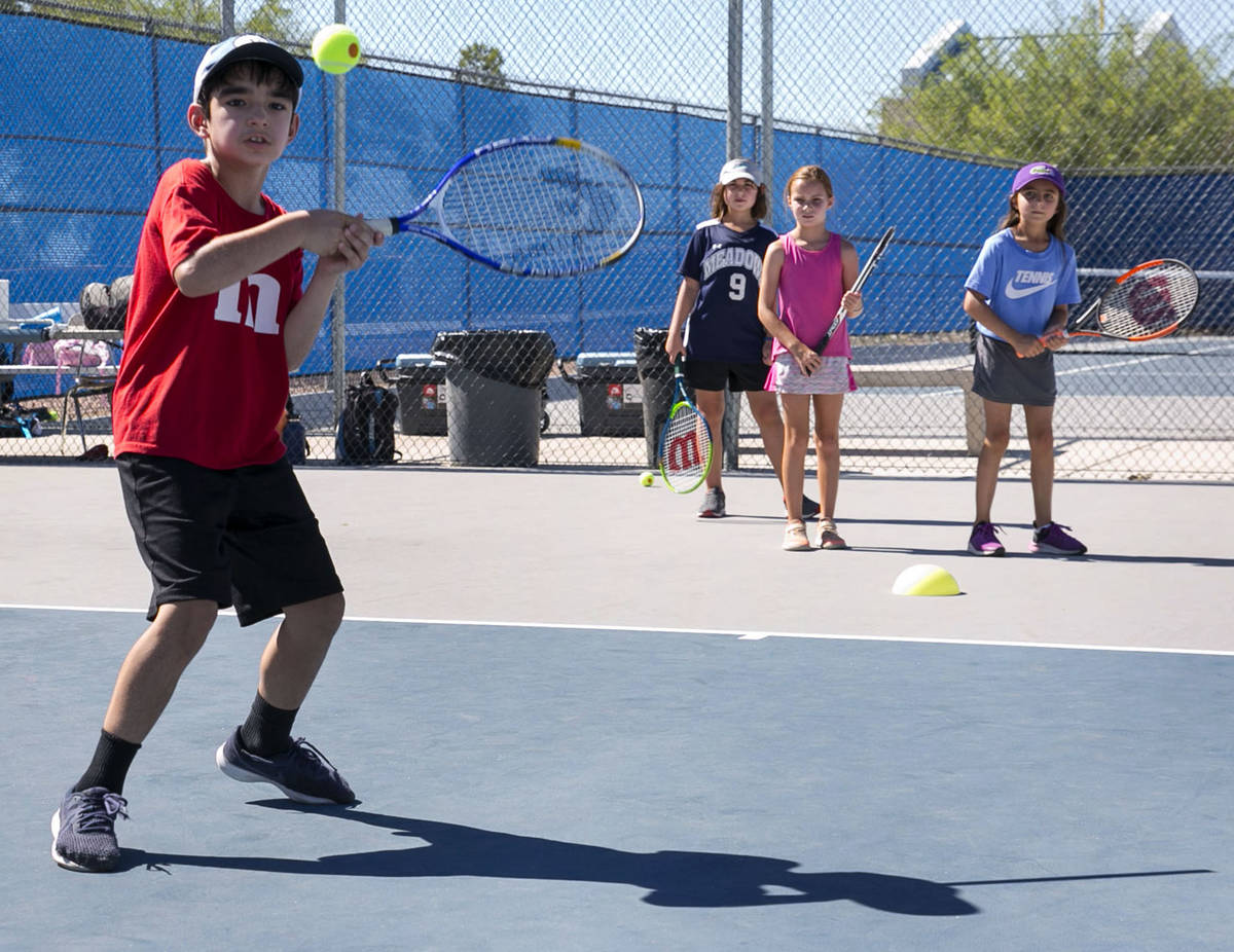 Julian Chaudhry, 8, returns the ball as he plays tennis at Camp Mustang at The Meadows School o ...