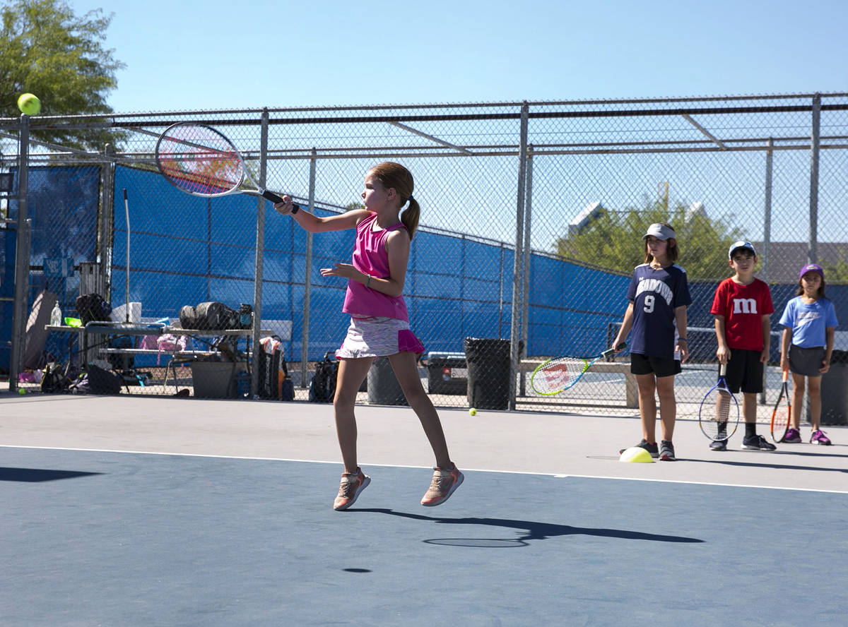 Jemma Michael, 7, returns the ball as she plays tennis at Camp Mustang at The Meadows School on ...