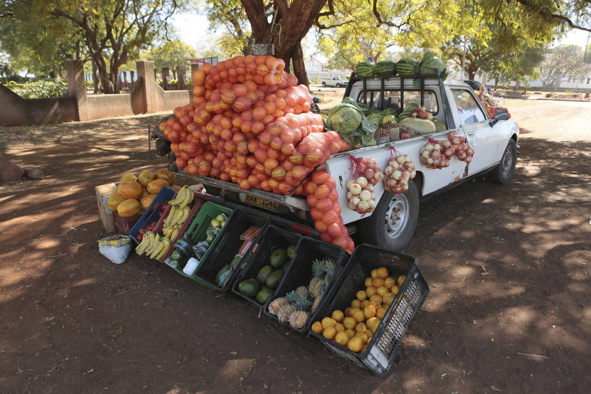 A car displays fruits and vegetables while selling them by the side of a busy road in Harare, Z ...
