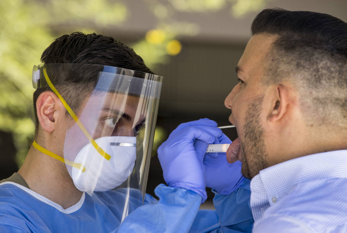 Nevada National Guard soldier PFC Nikolas Herrera, left, inserts a swab into the mouth of Paulo ...