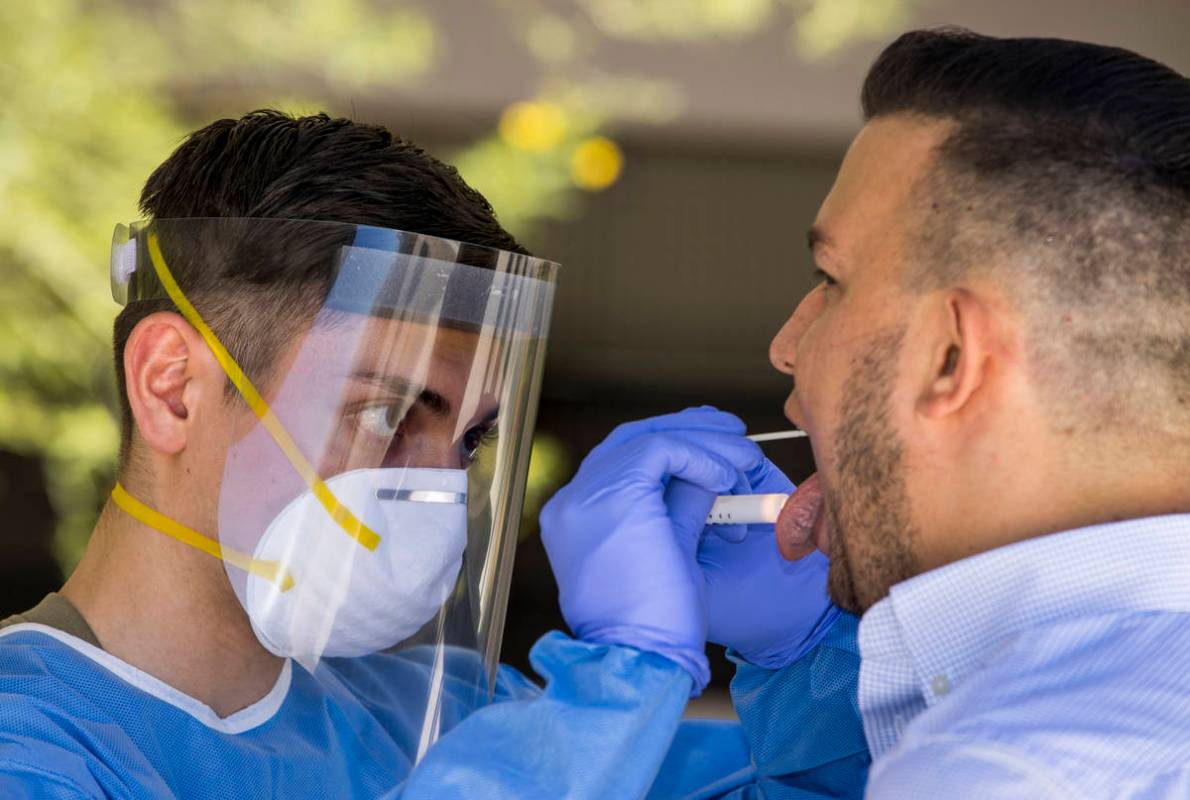 Nevada National Guard soldier PFC Nikolas Herrera, left, inserts a swab into the mouth of Paulo ...