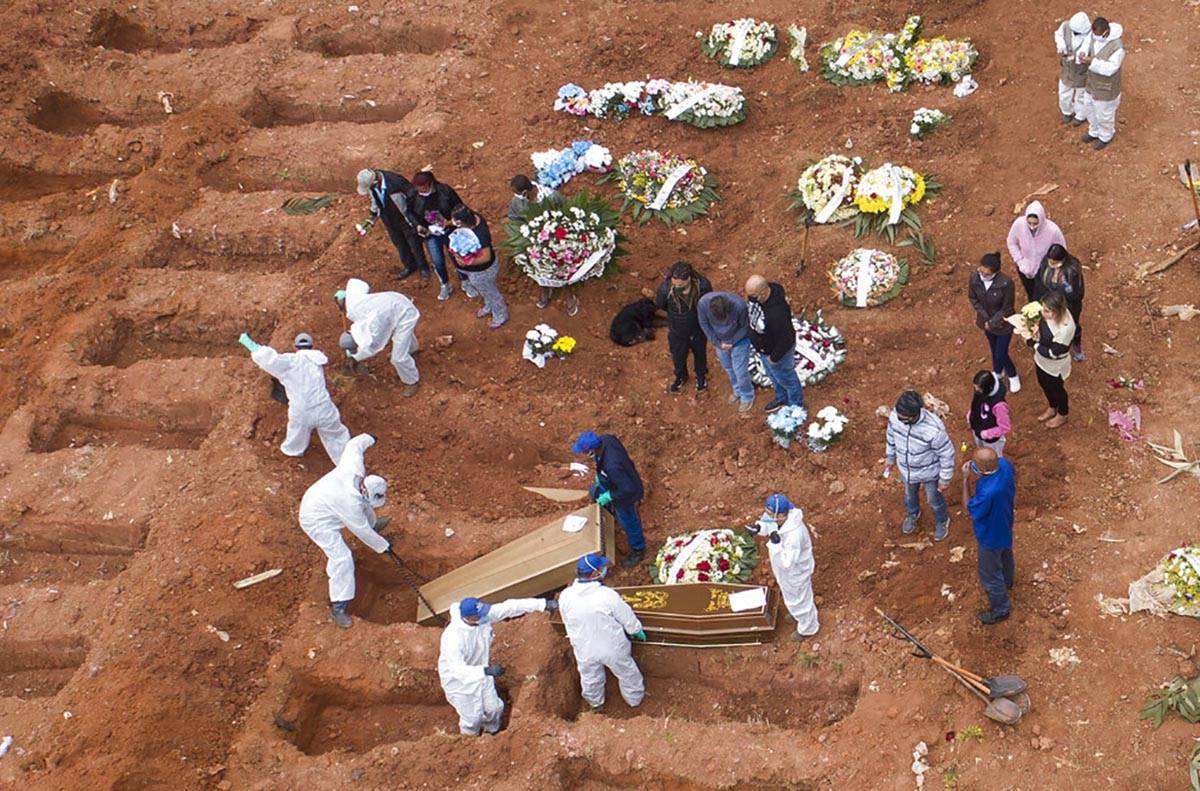 Cemetery workers in protective clothing bury victims of the new coronavirus at the Vila Formosa ...