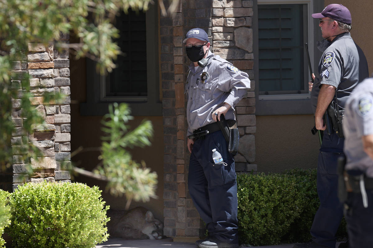 Multi-agency officers stand in front of a home after a mountain lion was located and tranquiliz ...