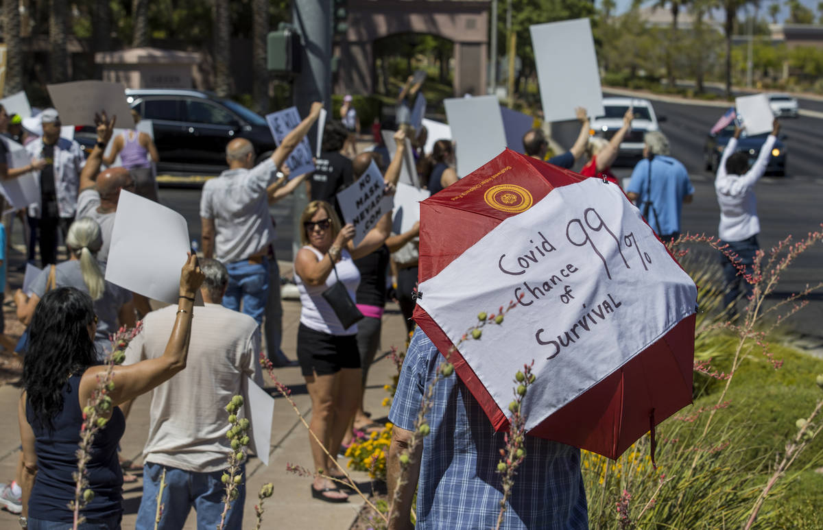 Protesters hold signs and chant slogans during a No Mask Nevada PAC rally along South Green Val ...