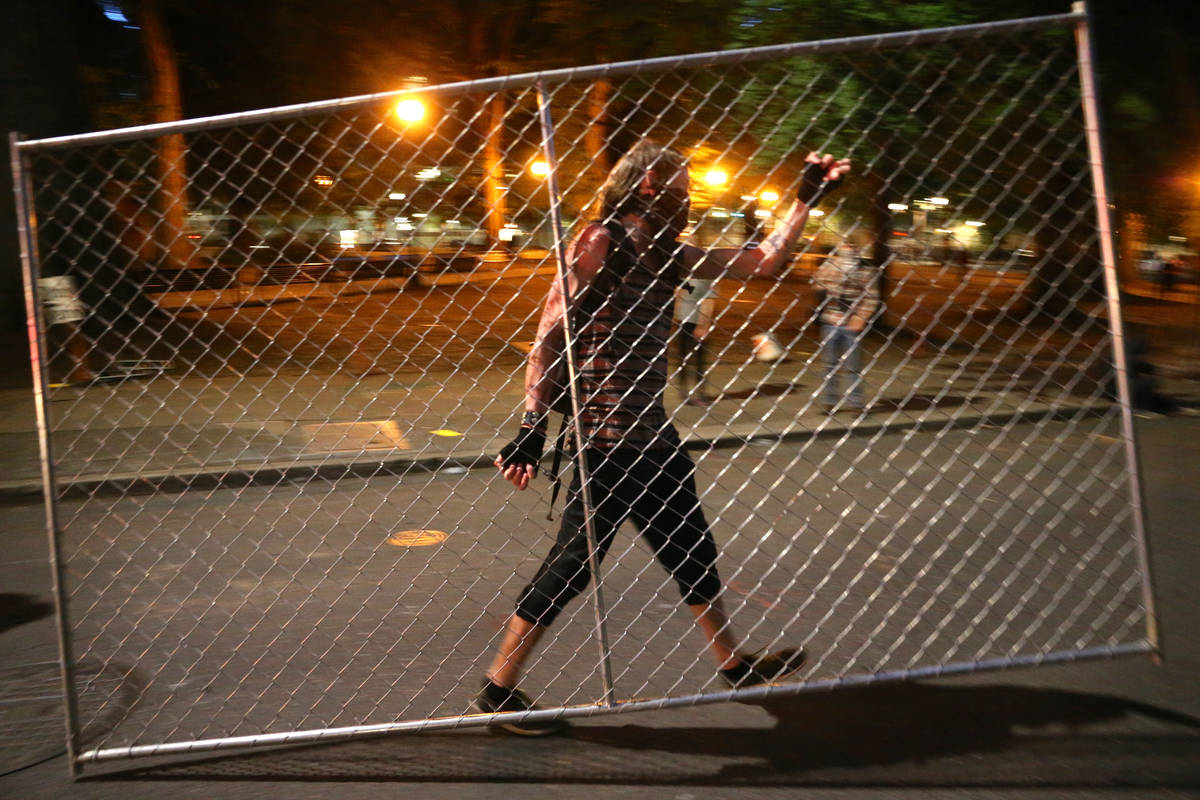 Protesters relocate a fence in front of the Justice Center, Saturday, July 18, 2020, during ano ...