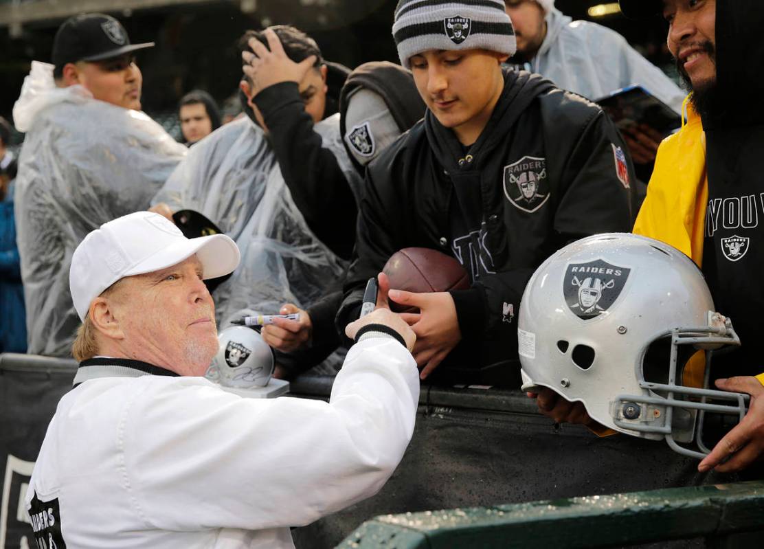 Oakland Raiders owner Mark Davis signs autographs for fans before an NFL football game between ...
