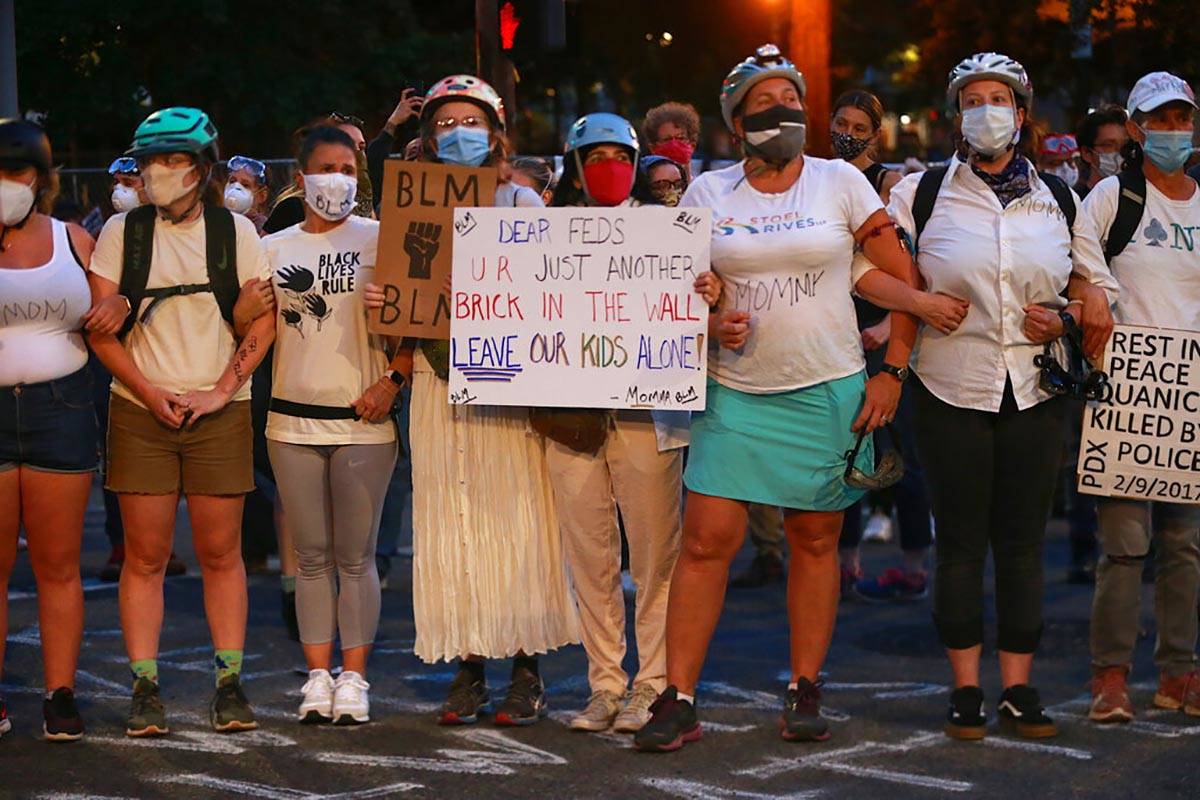 A group of mothers stand arm-in-arm outside the federal building and Justice Center in downtown ...