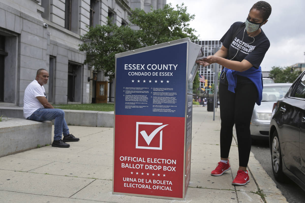 A woman drops her mail-in ballot into a drop box in Newark, N.J., Tuesday, July 7, 2020. New Je ...