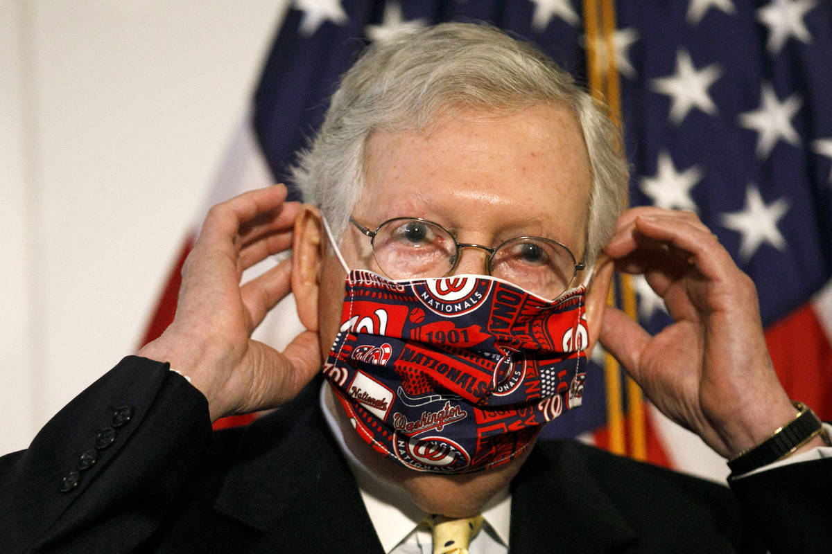 Senate Majority Leader Mitch McConnell of Ky., replaces his face mask after speaking at news co ...