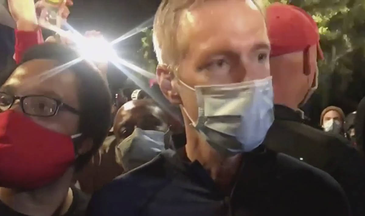 In this image made from video released by Karina Brown, Portland Mayor Ted Wheeler, right, stan ...