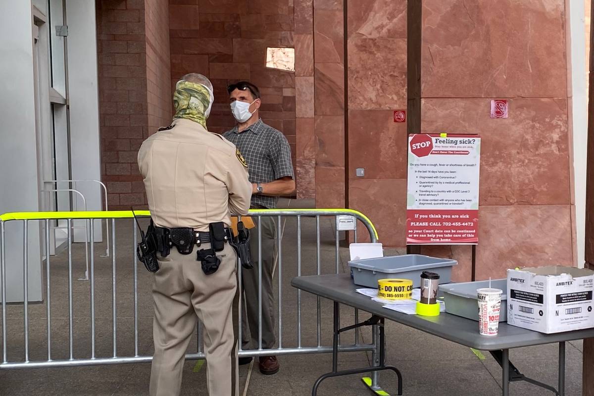 Masked marshals guard the entrance to the Regional Justice Center in Las Vegas, where a mask or ...