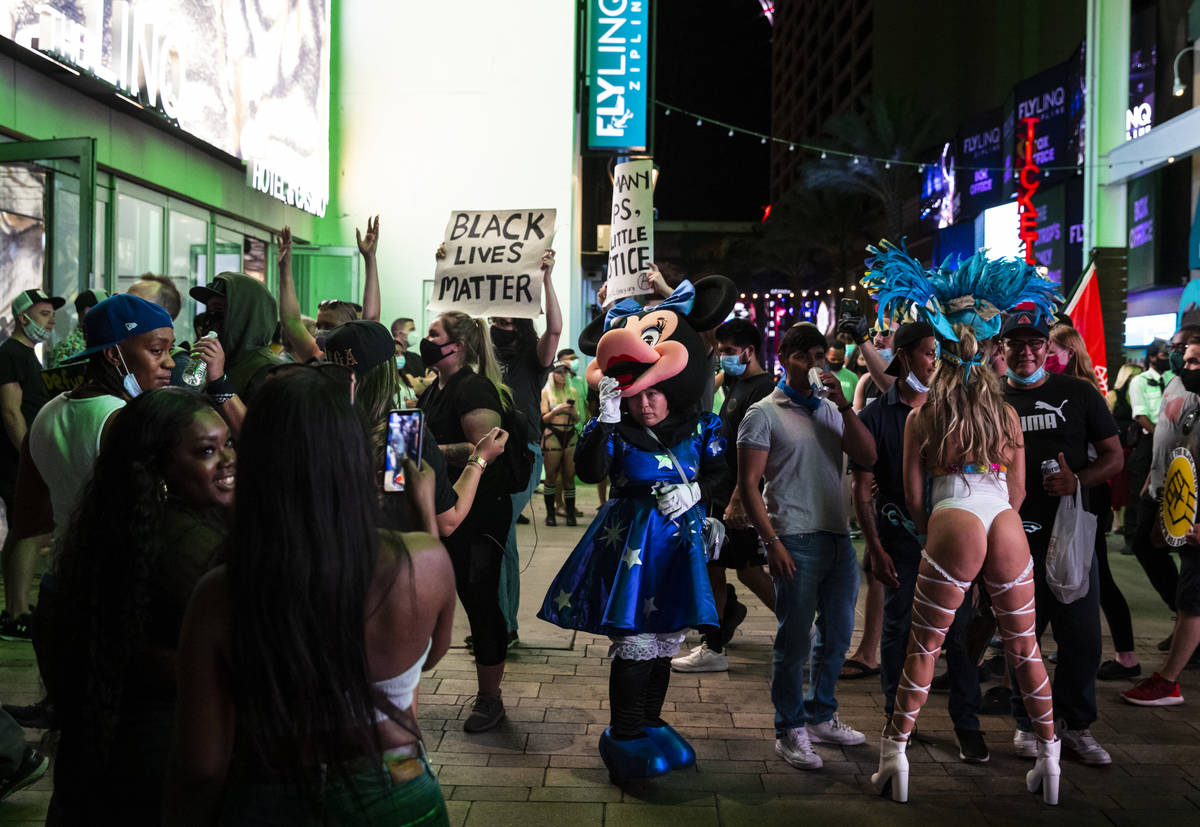 Street performers look as Black Lives Matter protesters walk on the Las Vegas Strip on Saturday ...