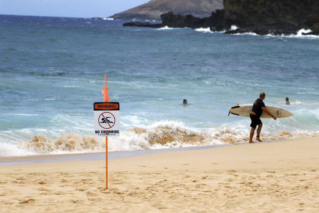 A surfer leaves the water in Honolulu, Saturday, July 25, 2020, as Hurricane Douglas approaches ...
