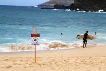 A surfer leaves the water in Honolulu, Saturday, July 25, 2020, as Hurricane Douglas approaches ...