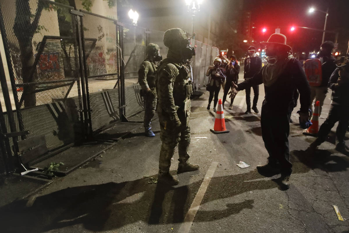 A demonstrator argues with a federal officer during a Black Lives Matter protest at the Mark O. ...
