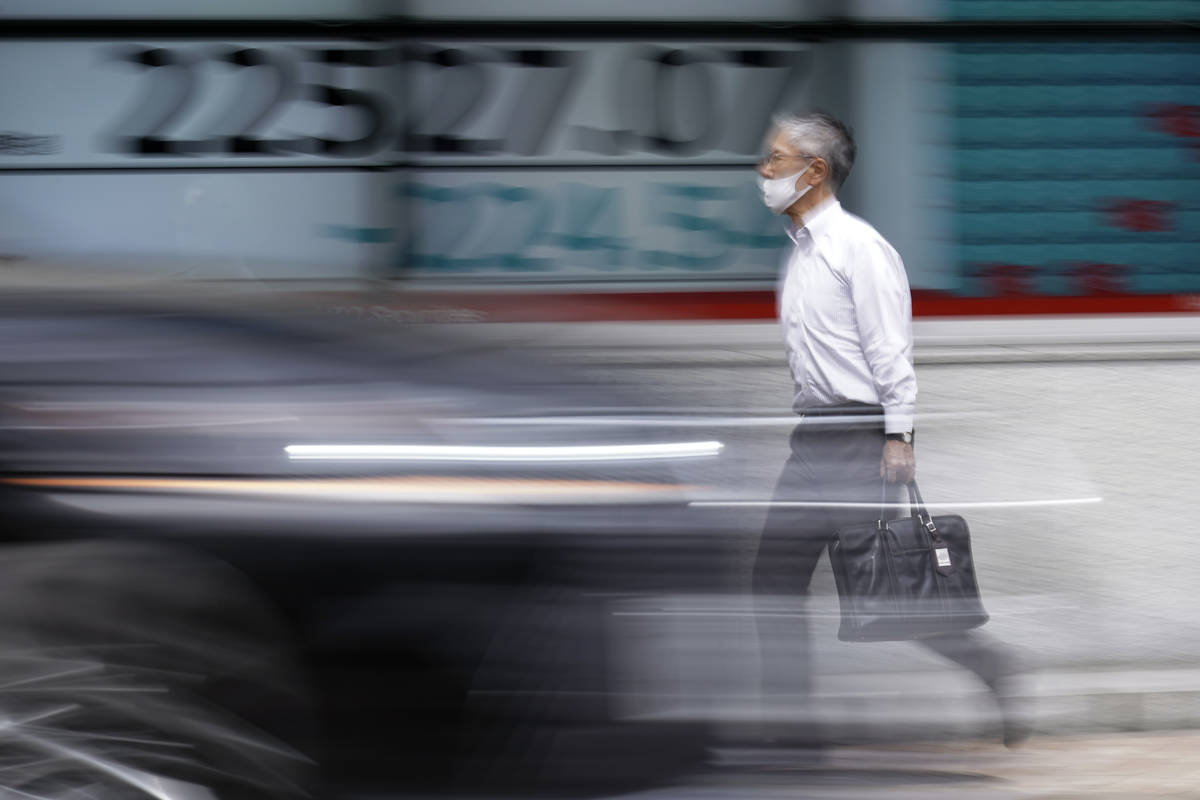 A man walks past an electronic stock board showing Japan's Nikkei 225 index at a securities fir ...