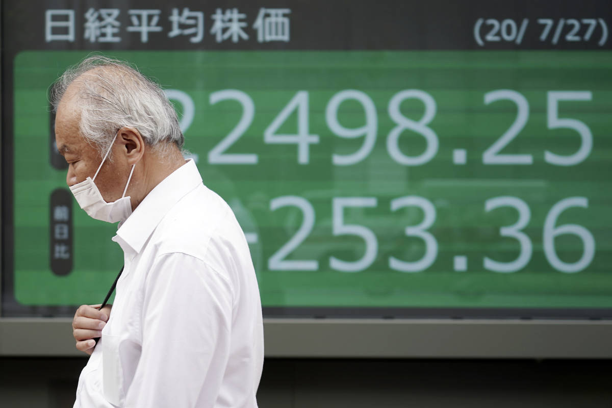 A man walks past an electronic stock board showing Japan's Nikkei 225 index at a securities fir ...