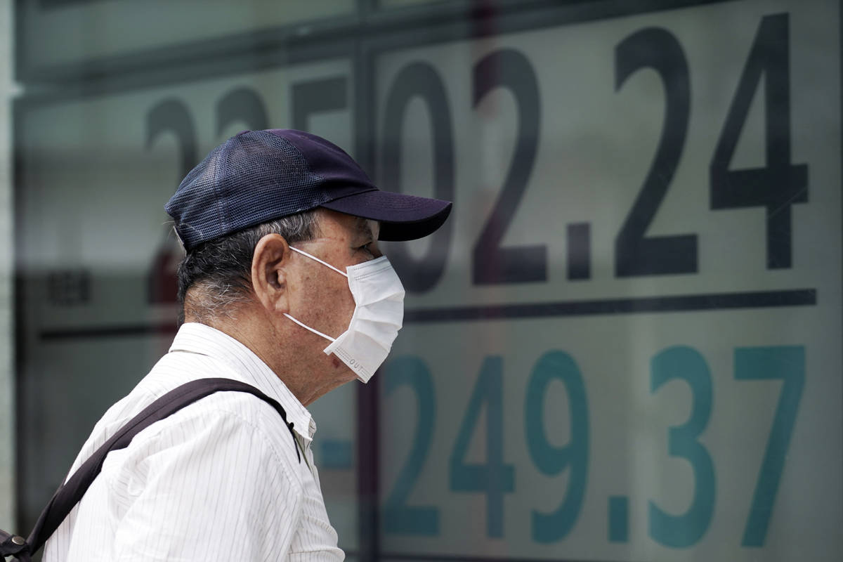 A man looks at an electronic stock board showing Japan's Nikkei 225 index at a securities firm ...