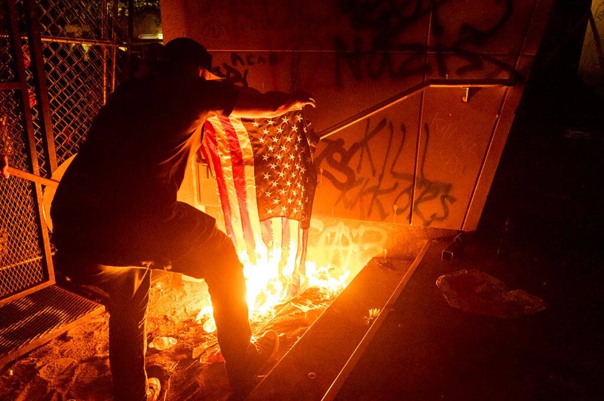 A Black Lives Matter protester burns an American flag outside the Mark O. Hatfield United State ...