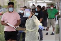 In this July 22, 2020, file photo, people line up behind a health care worker at a mobile Coron ...