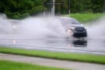 In an image made from video, cars drive through high water on a road in Canovanas, Puerto Rico, ...