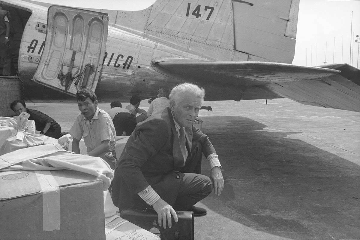 Don King Middleton, foreground, Britain's charge d'affairs in Phnom Penh, takes cover under the ...