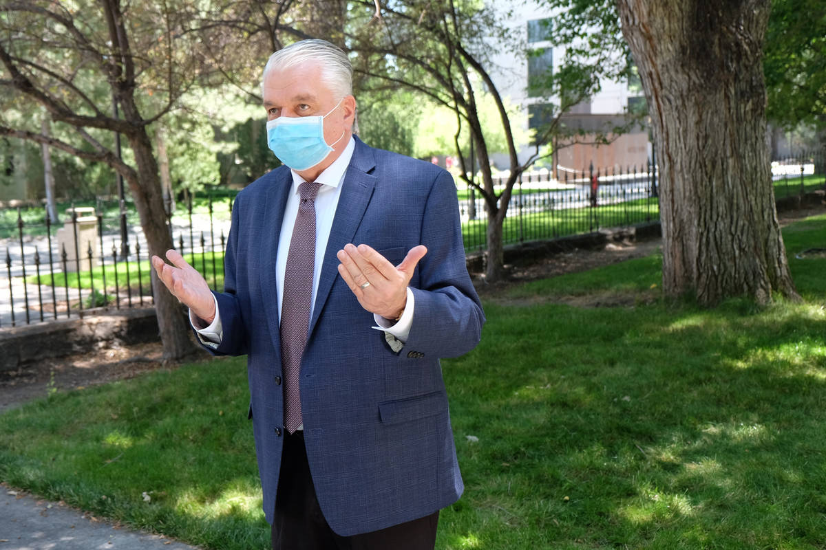 A masked Gov. Steve Sisolak speaks to reporters outside the Capitol discussing spending cuts an ...