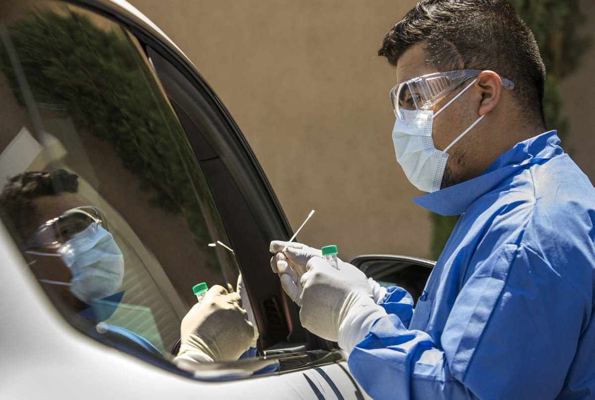 Practice Manager Jose Tirana conducts a COVID-19 test on a patient in the parking lot at Sahara ...