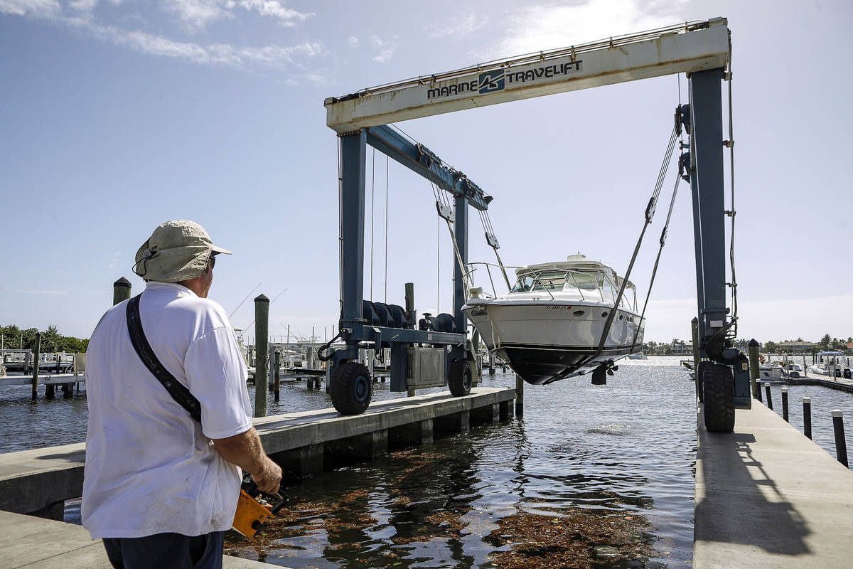Brett Hand controls a Marine Travelift with a hand held remote to lift boats out of the water a ...