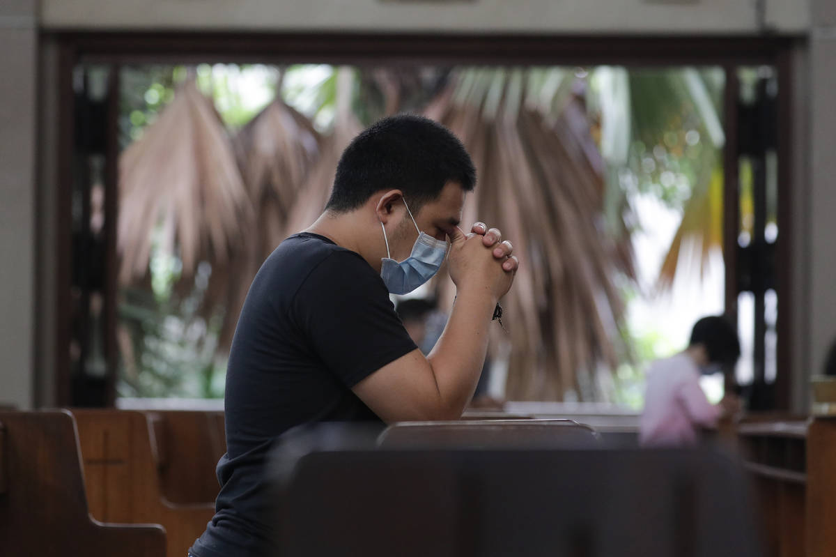 A man prays with only a few other parishioners as a measure to prevent the spread of COVID19 du ...