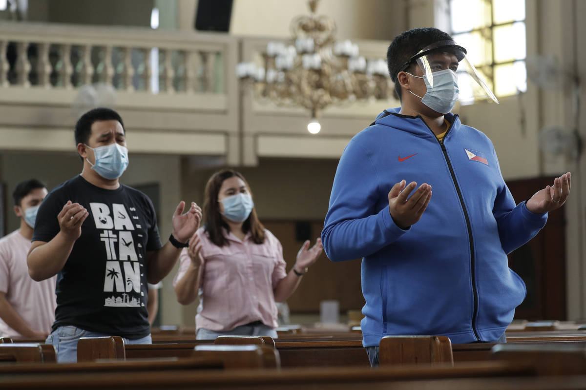 Parishioners wearing masks as a measure to prevent the spread of COVID19 pray during a Mass at ...