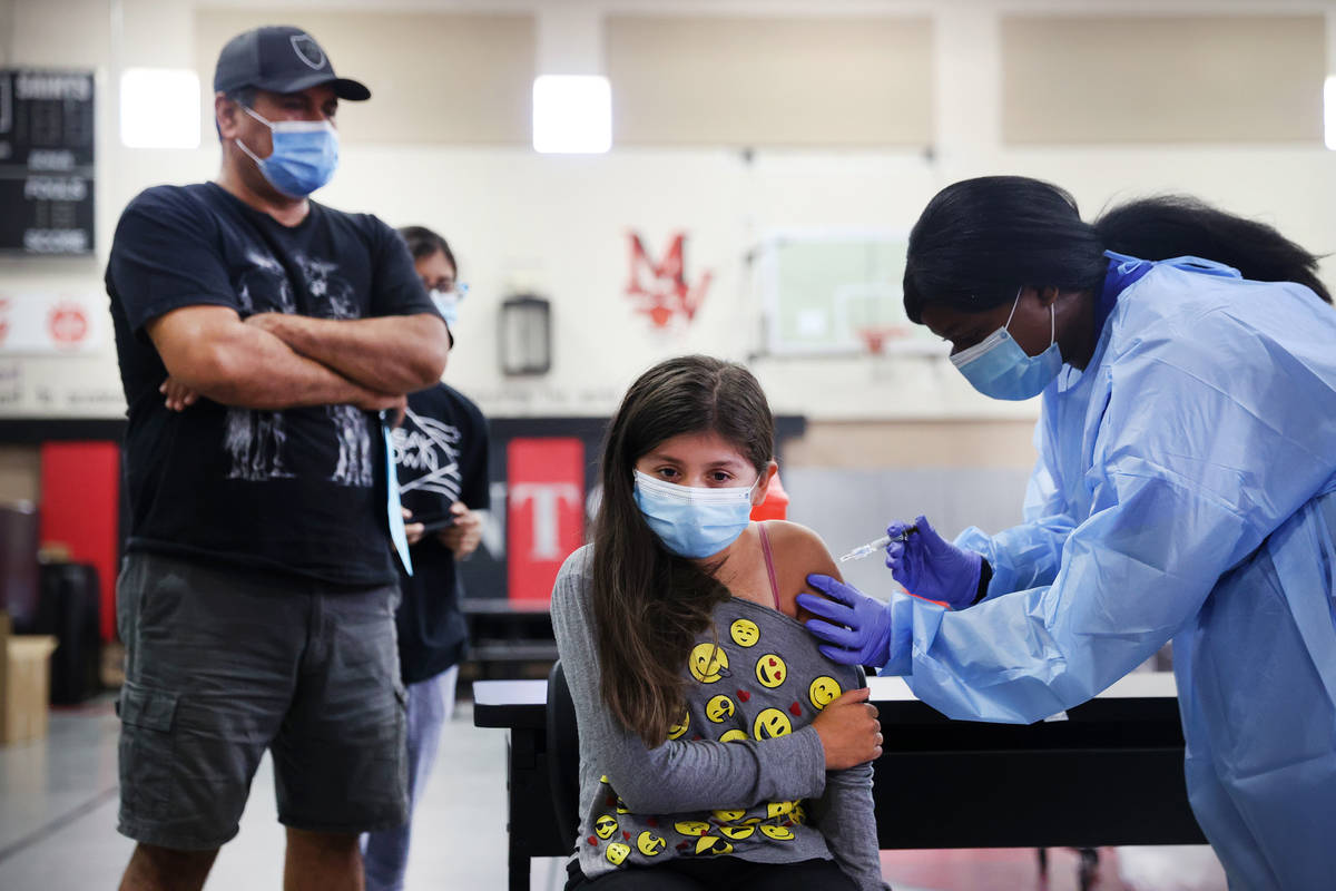 Abdon Ayala, from left, look over as his daughter Brianna, 11, gets a vaccine from registered n ...