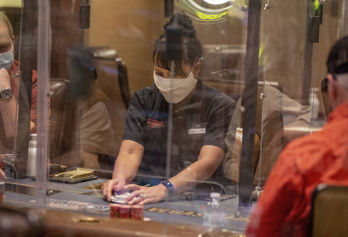 Poker dealer Melissa Moses deals an eight-handed game protected by plexiglass dividers, at the ...