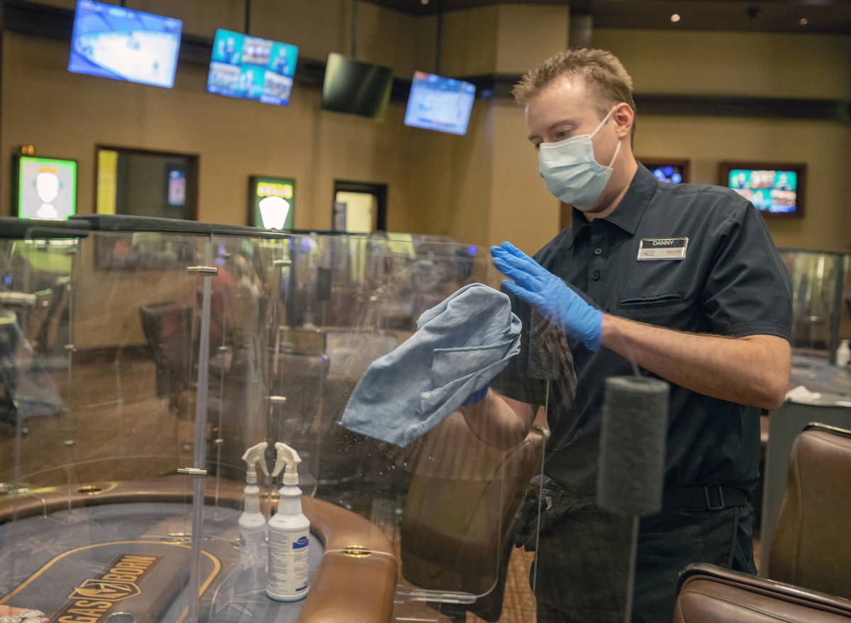 Poker dealer Daniel Wilson sanitizes plexiglass dividers, at the Red Rock Resort poker room in ...