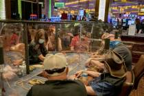Individuals play eight-handed poker games using plexiglass dividers between the players in the ...