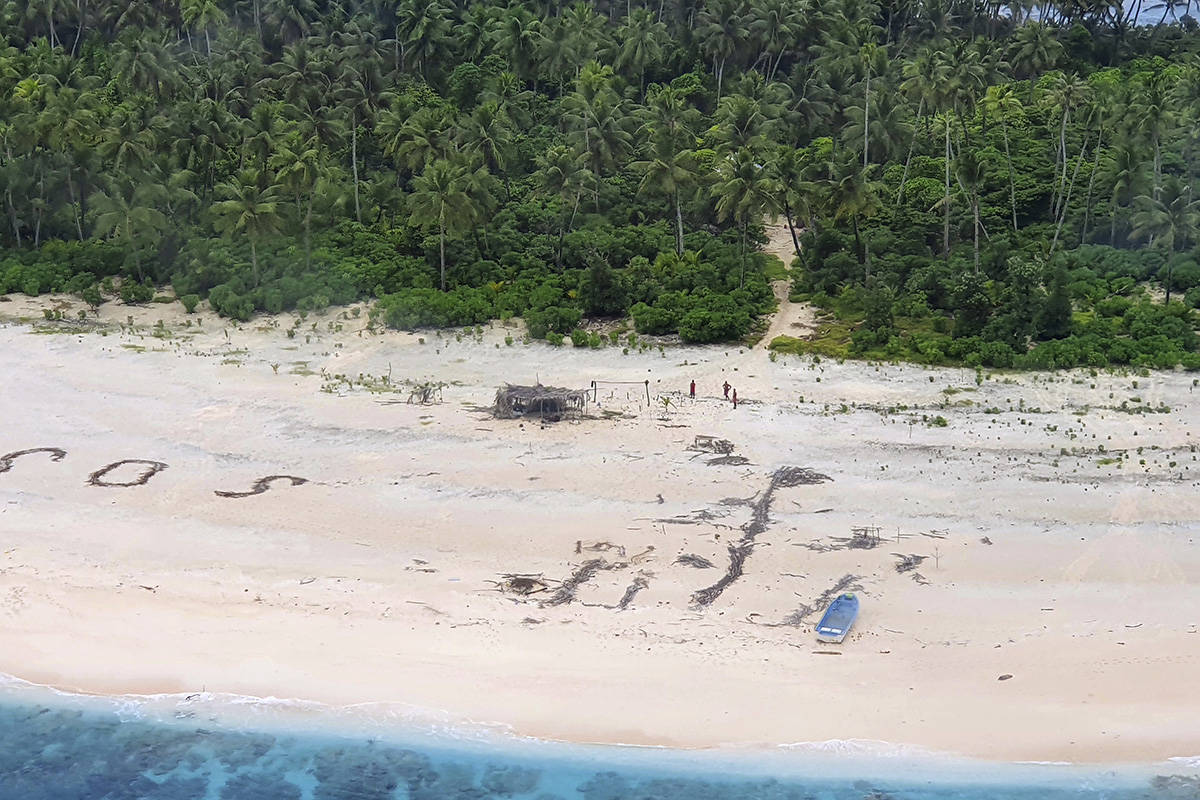 In this photo provided by the Australian Defence Force, three men stand the beach on Pikelot Is ...