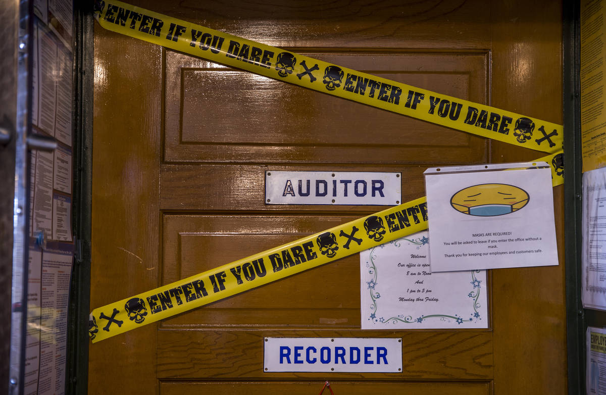 A face covering sign and a little humor mark the Auditor and Recorder office door within the Es ...