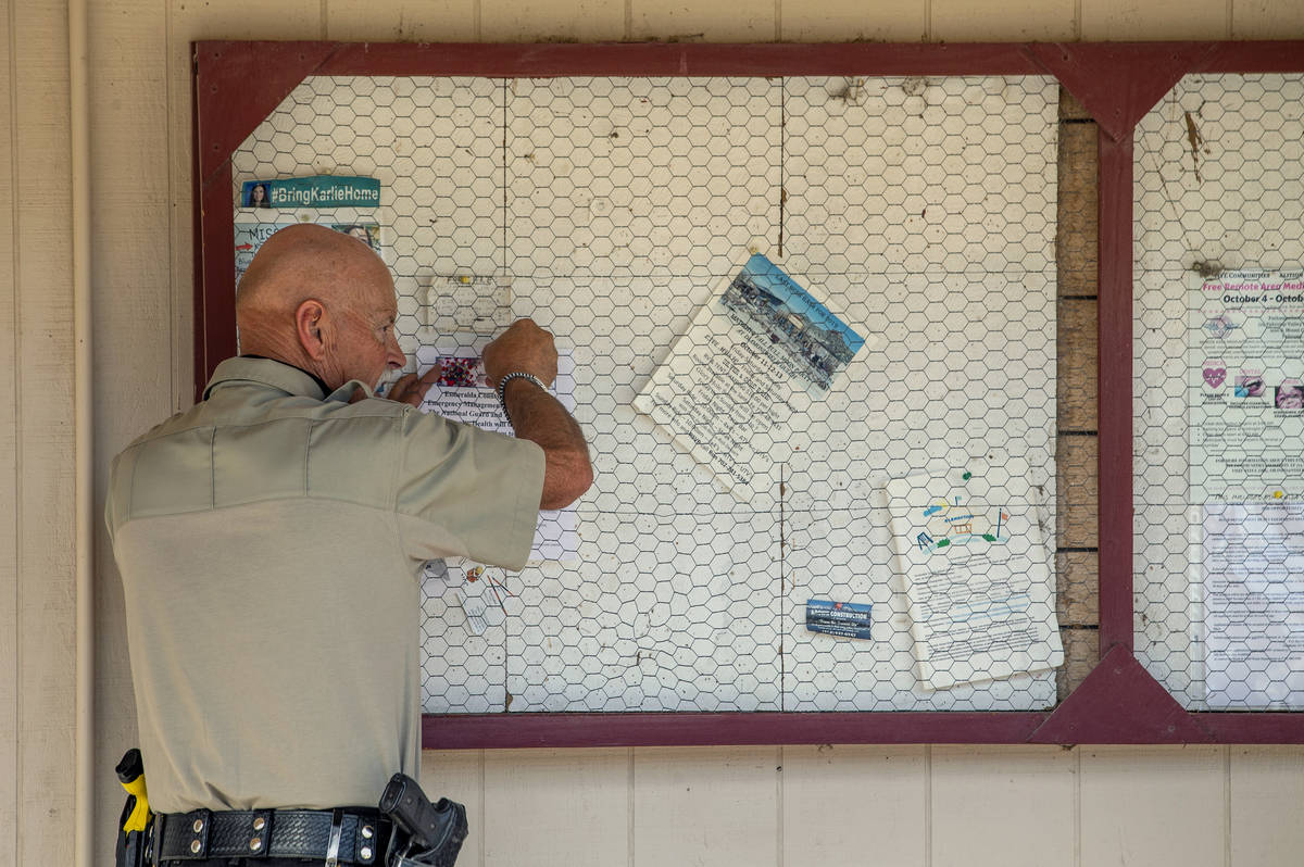 Sheriff's Deputy Ken Aldrich hangs a new COVID-19 drive-thru testing notice at the Esmeralda Ma ...