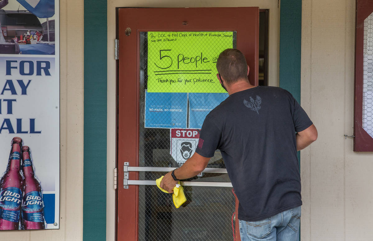 Jim Pringle wipes down the front door at the Esmeralda Market which enforces a face covering po ...