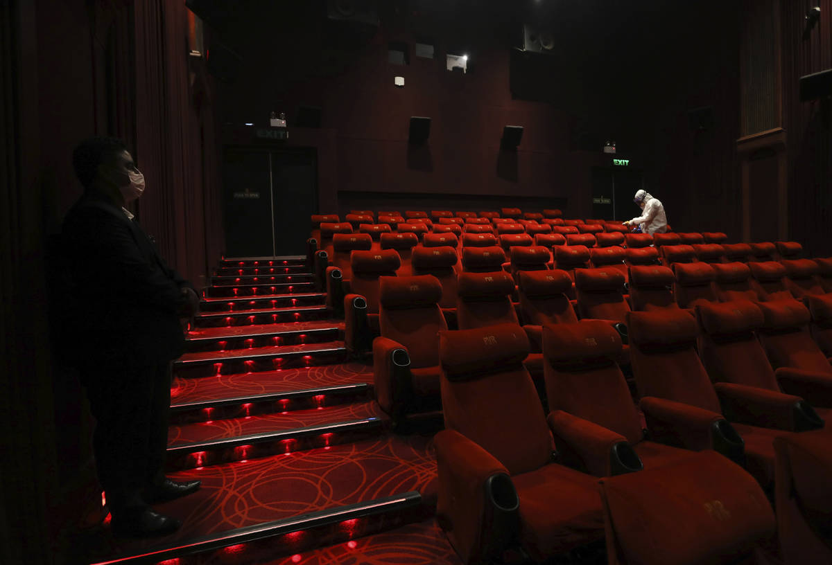 Workers of PVR cinemas, a multiplex cinema chain,sanitizes a theater during a press preview to ...