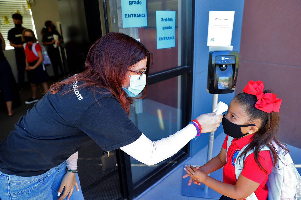 Lianna Garcia rubs her hands with sanitizer as she gets her temperature taken by Vanessa Sanche ...