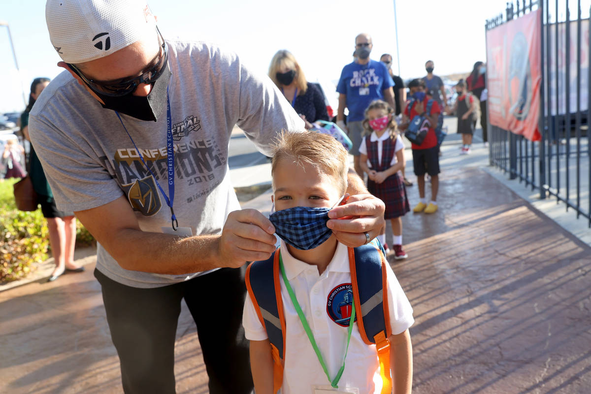Kindergartner Dominic Martin, 6, gets his mask adjusted by his father Jason Martin on the first ...
