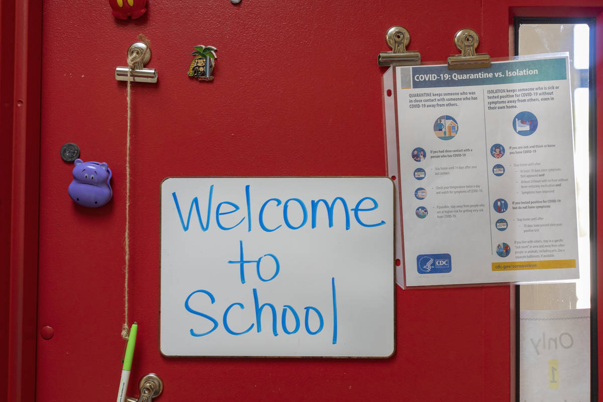 A sign welcoming students to school next to a COVID-19 guide is seen in a classroom on the firs ...