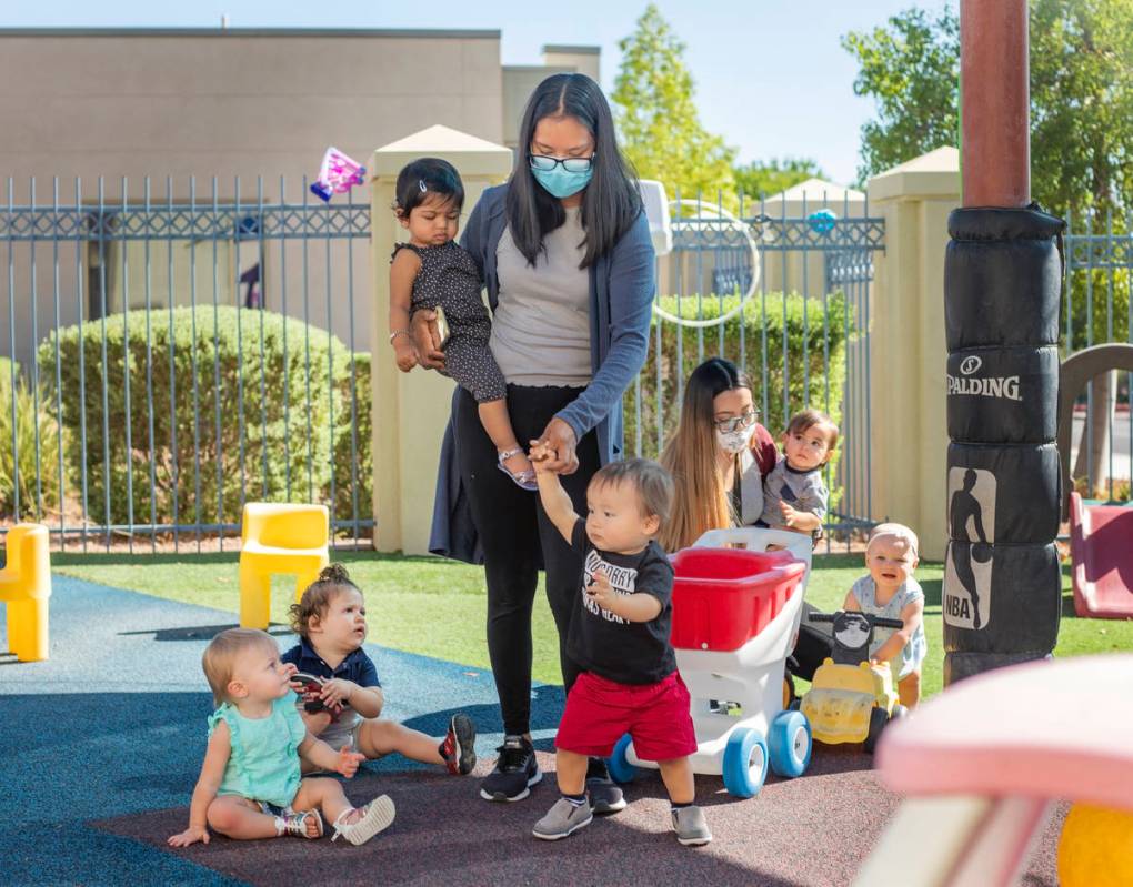 Assistant leads for the 12 to 18 months play outside during the first day of school at Shenker ...