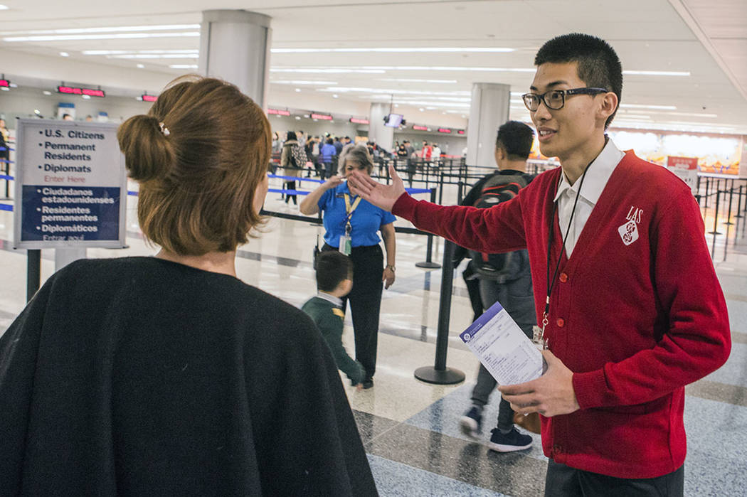 Shingling Guo, right, a Malarian-speaking ambassador, assists a passenger from Hainan Airline f ...
