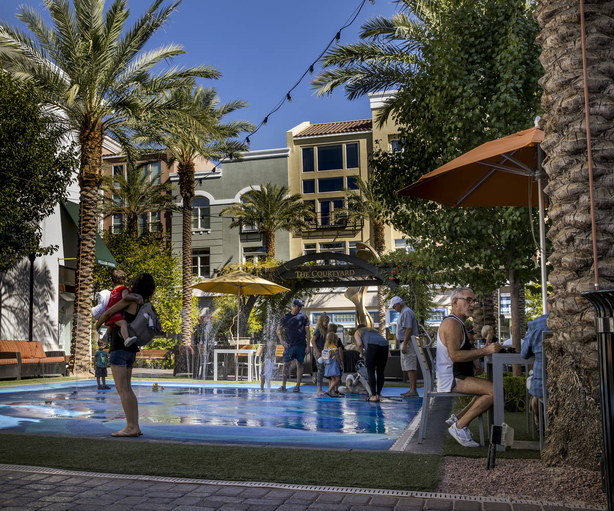 Visitors relax about the splash pad at The District at Green Valley Ranch on Friday, August 7, ...
