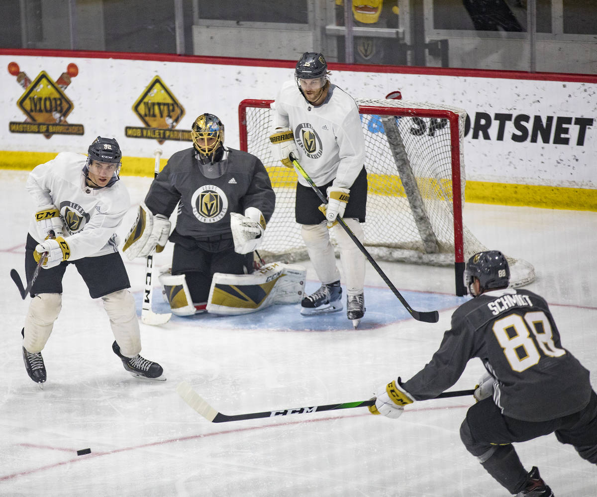 Golden Knights' Tomas Nosek (92) tries to steal the puck from Nate Schmidt (88) as players Jon ...